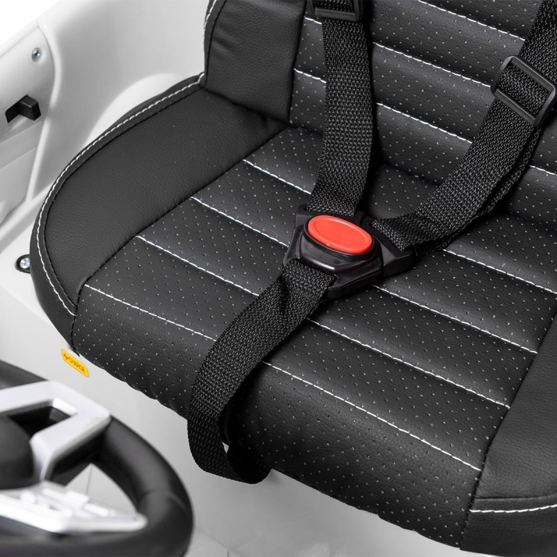 Cadeira preta de criança com cinto de segurança num veículo branco