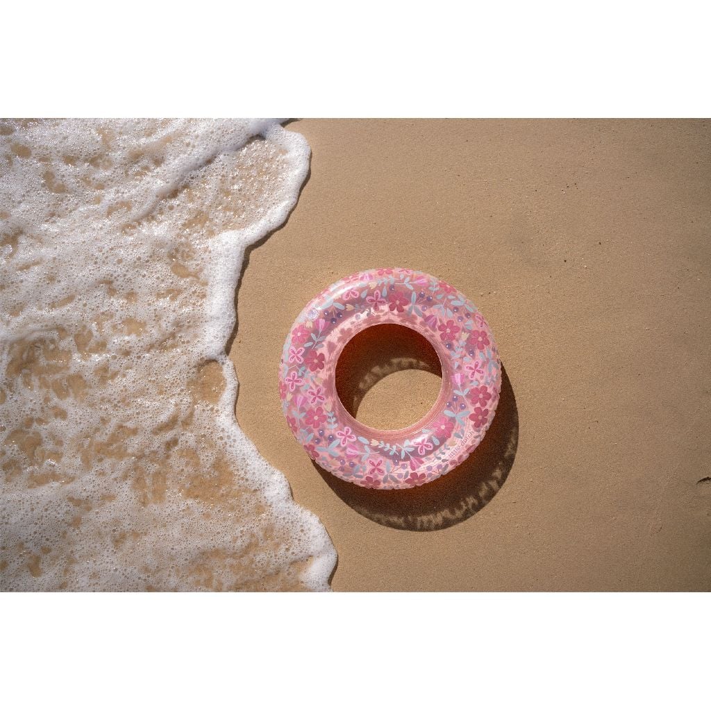 Bóia insuflável cor-de-rosa com padrão floral na areia junto ao mar