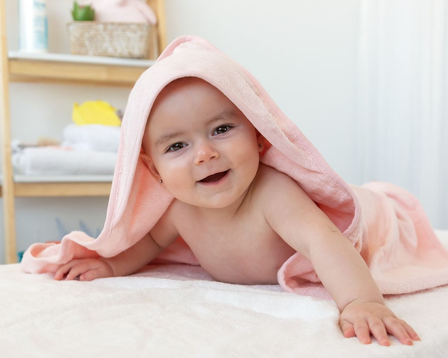 Bebé deitado coberto com toalha rosa com capuz