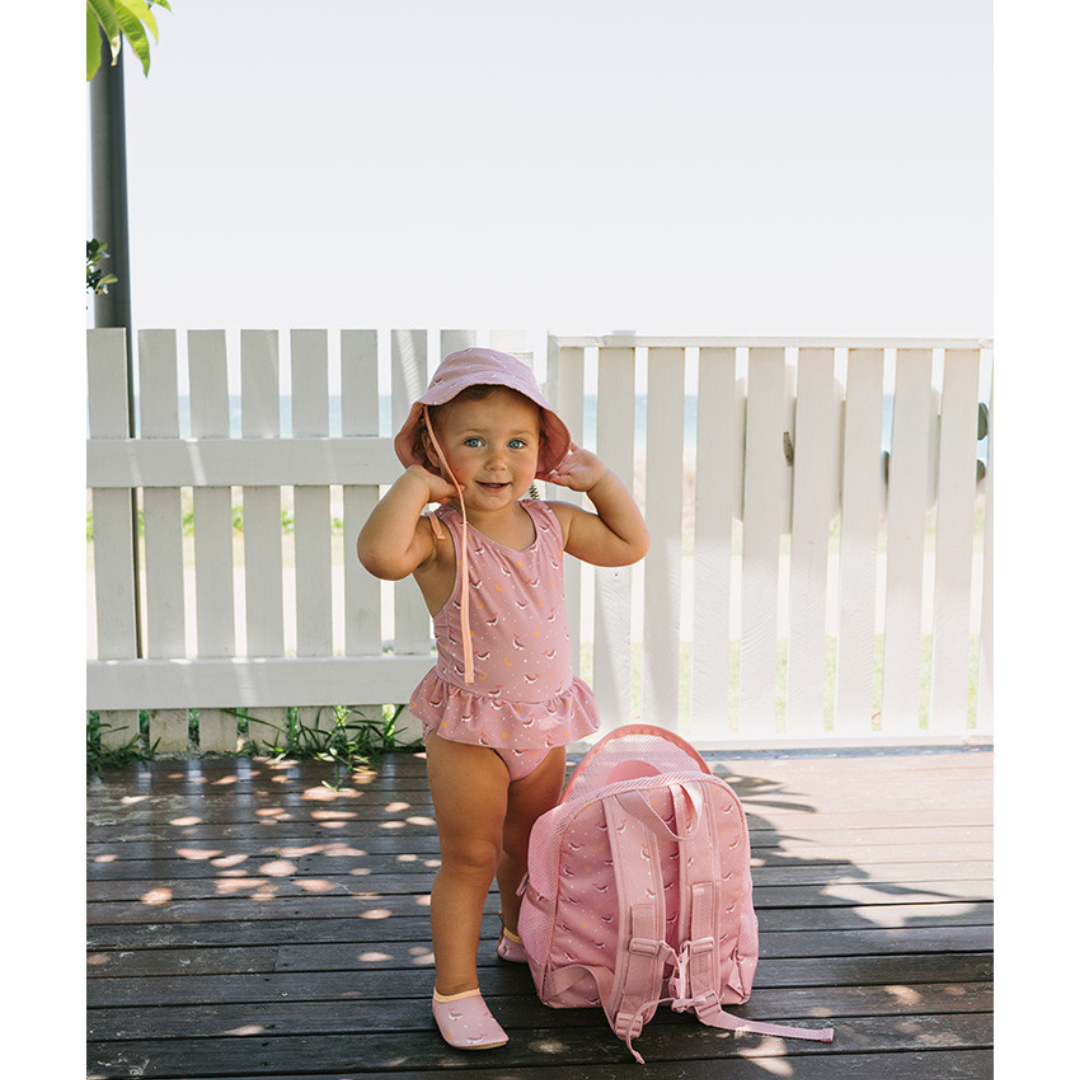 Criança com fato de banho rosa e mochila ao ar livre