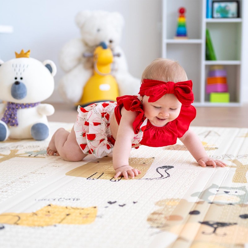 Bebé a engatinhar em tapete colorido com padrão de animais e brinquedos ao fundo