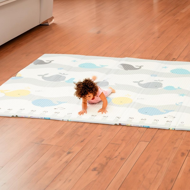 Tapete de bebé com padrão de baleias de cores azul, cinzento e amarelo.