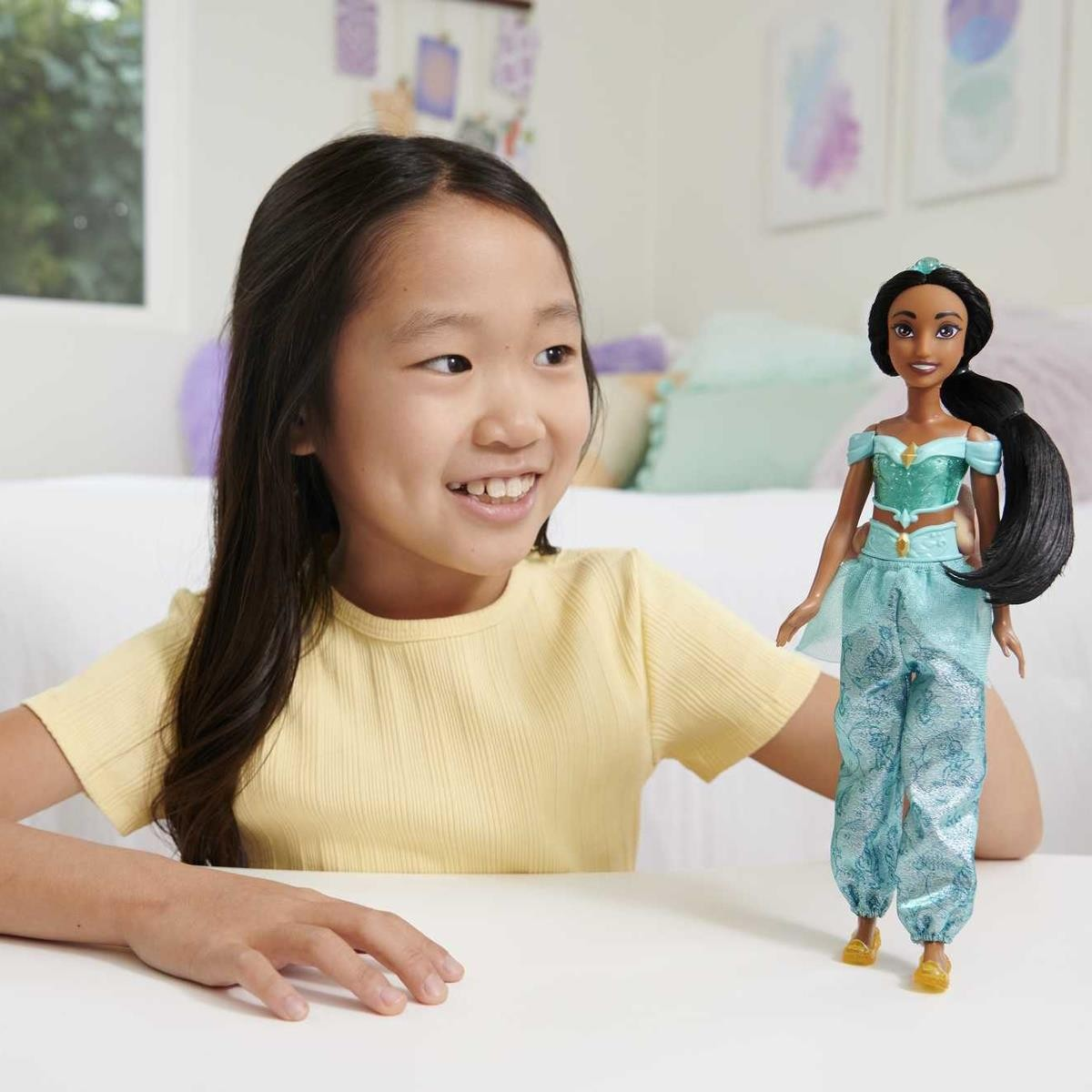 Menina a brincar com boneca princesa em mesa branca