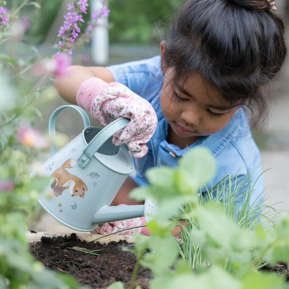 Menina a regar plantas com regador cinza claro decorado com cachorro