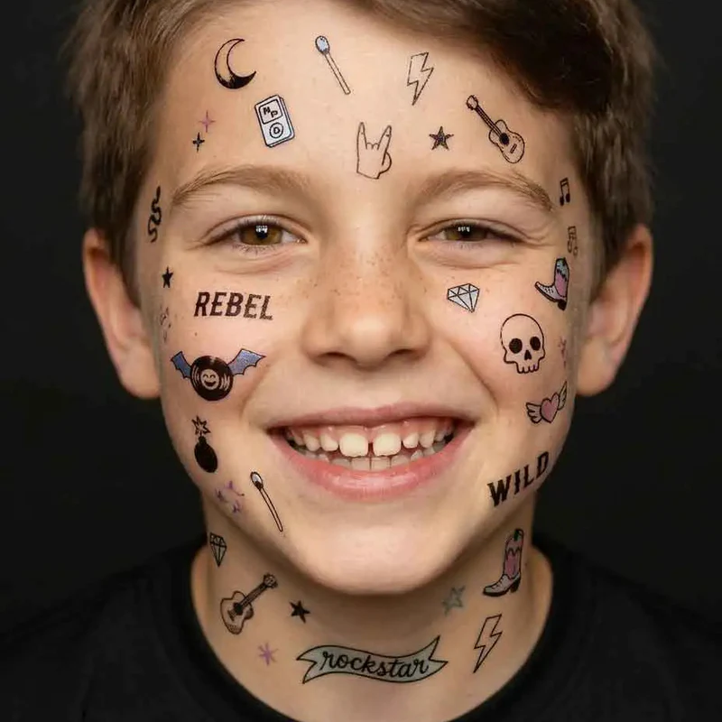 Menino sorridente com tatuagens temporárias de rock nas faces e pescoço