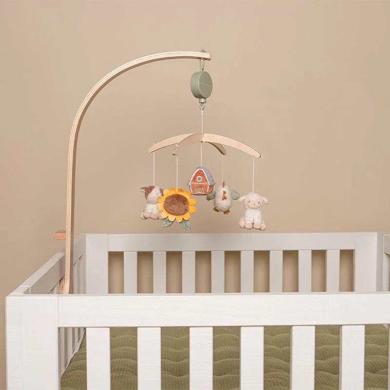Mobile de berço com personagens de animais e girassol, estrutura em madeira clara e berço branco com colchão verde.