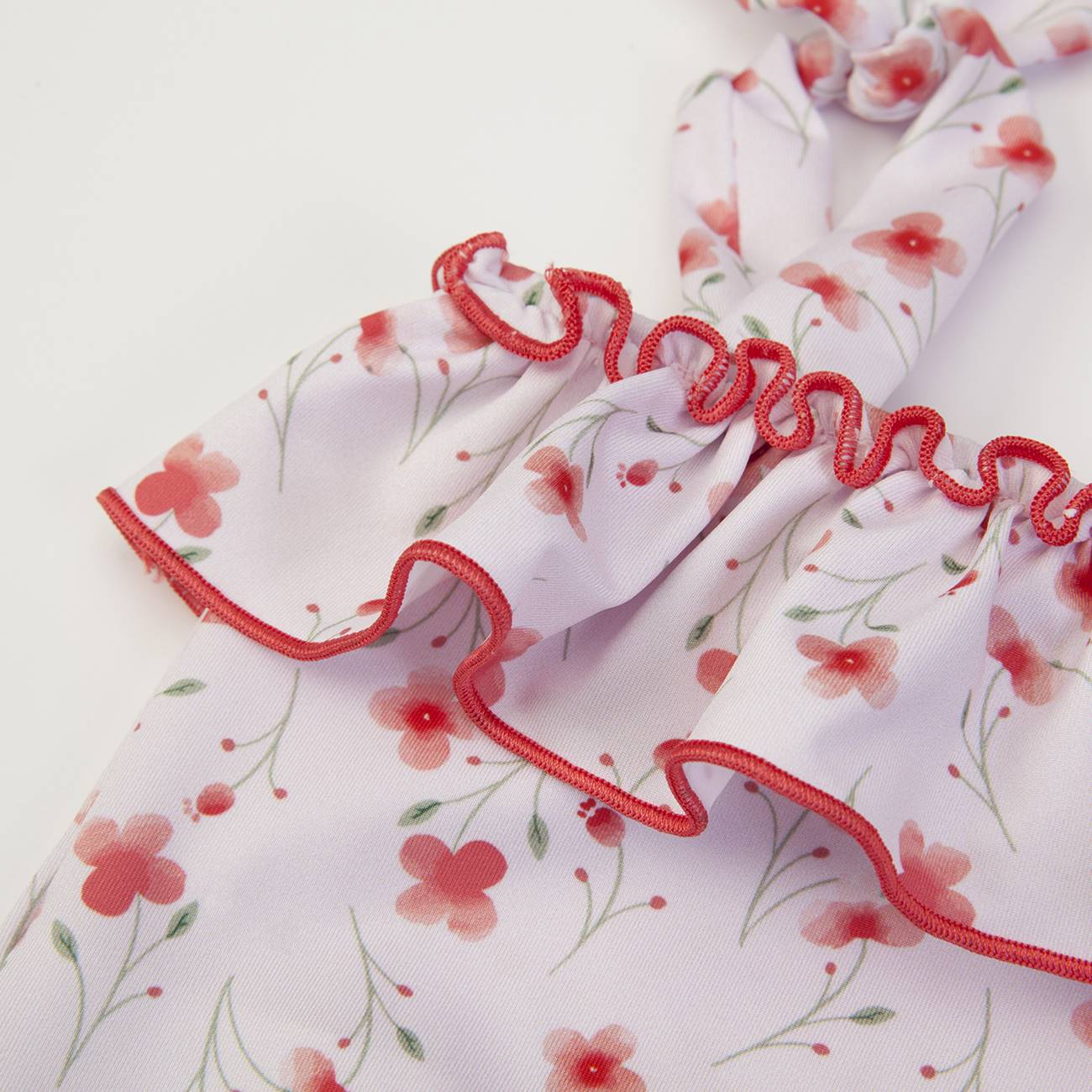 tecido floral branco com flores rosa e vermelhas e costura vermelha ondulada