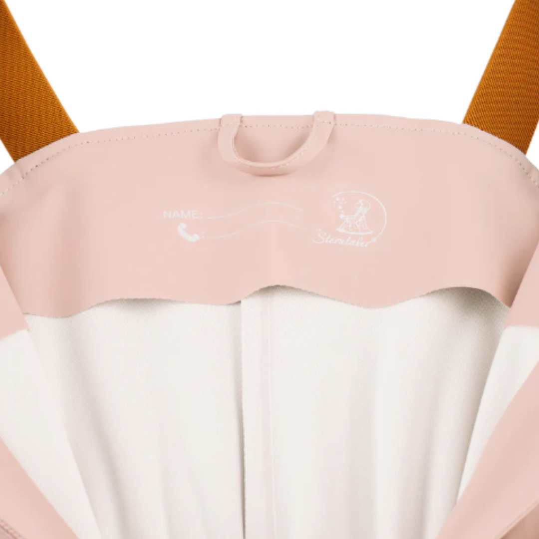Detalhe do interior de bolsa ou mochila rosa claro e branco com alças castanhas e texto Sterntaler