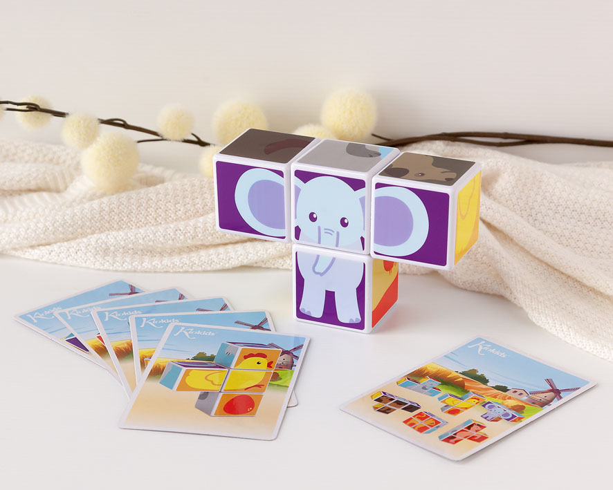 Cubos de papelão coloridos com elefante formado e cartões ilustrados sobre malha bege
