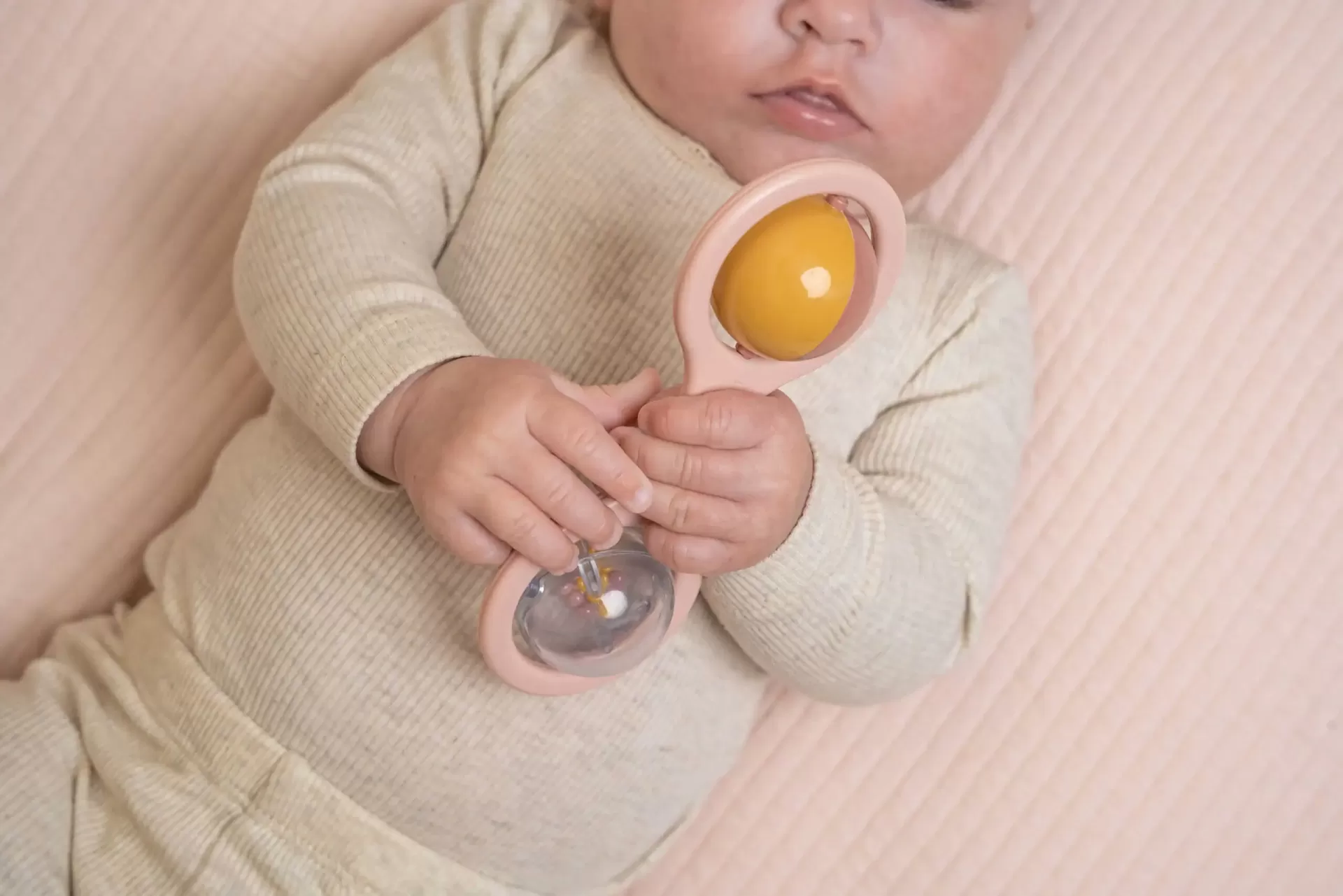 Bebé segurando brinquedo de mão com esfera amarela e partes transparentes