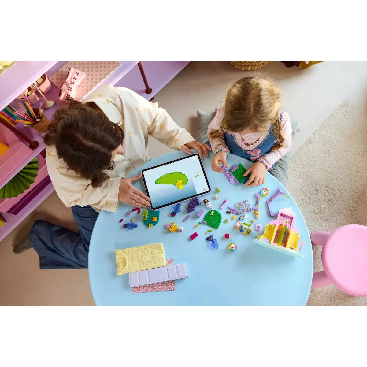 Crianças a brincar com peças de construção coloridas numa mesa azul com tablet digital
