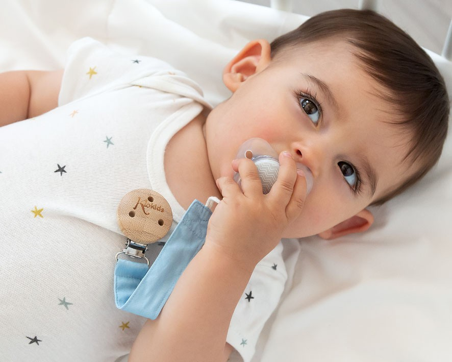 Bebé a segurar chupeta com mola de madeira