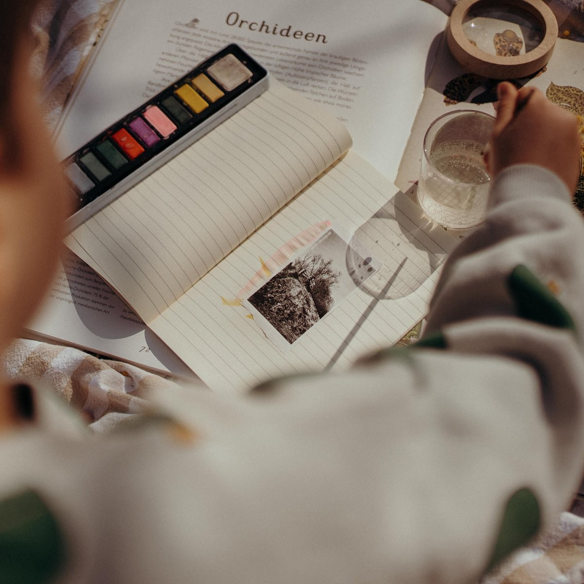 Pessoa a pintar com aguarelas num caderno com uma foto colada