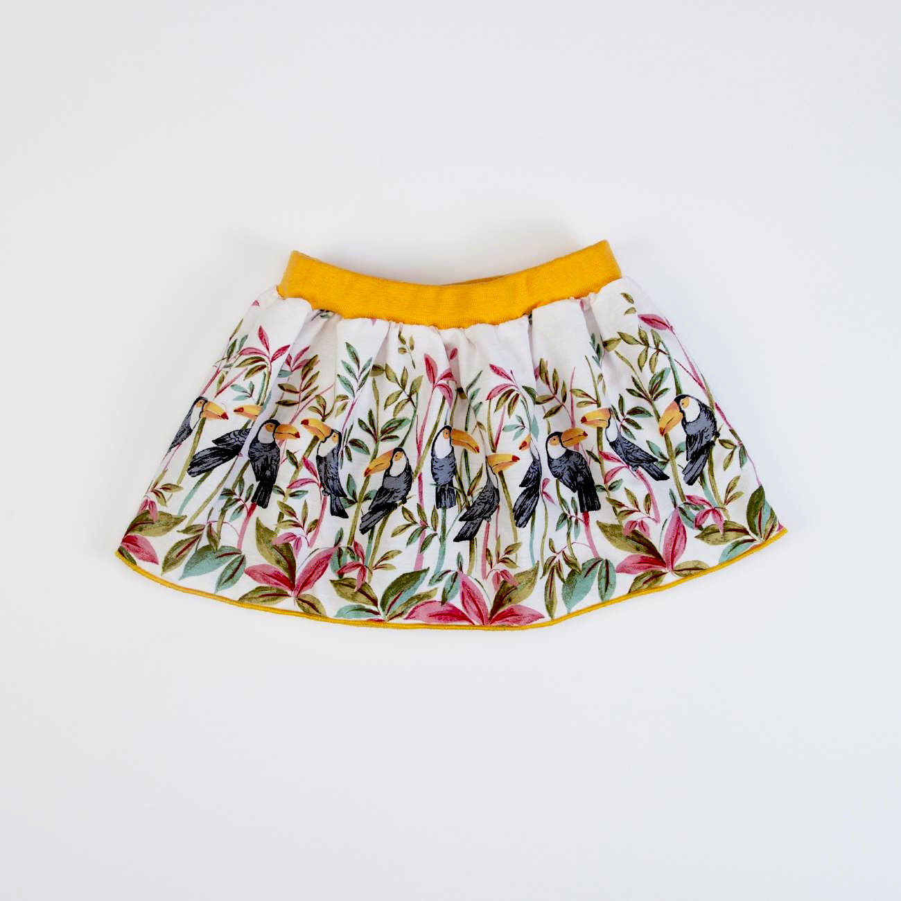 Saia branca com padrão de pássaros e plantas, cós amarelo.