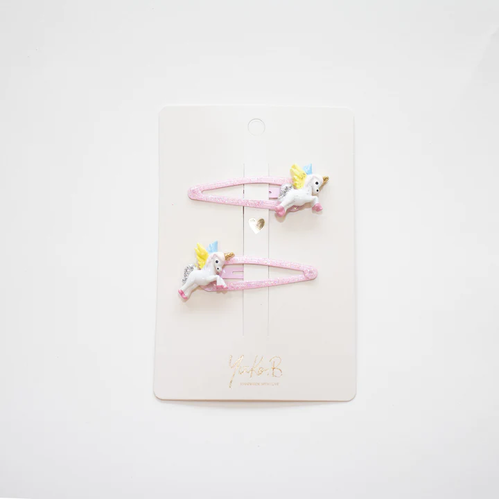 Duas molas de cabelo cor-de-rosa com unicórnios em tecido em cartolina branca