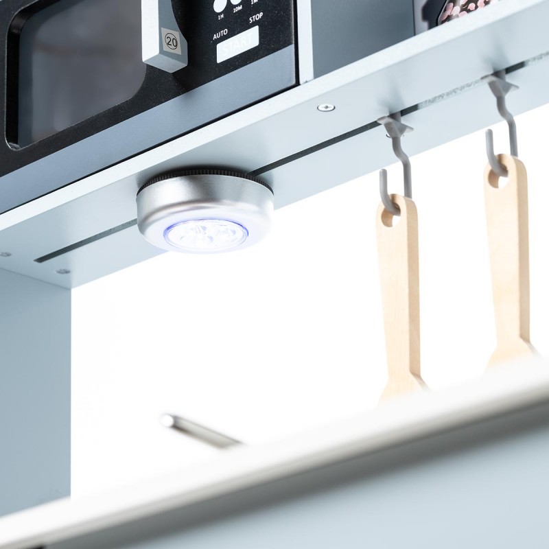 Luz LED branca sob armário cinza com utensílios de cozinha em madeira pendurados em ganchos