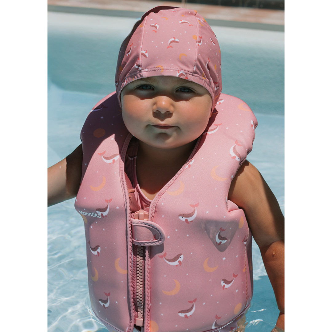 Criança com colete salva-vidas rosa com golfinhos na piscina