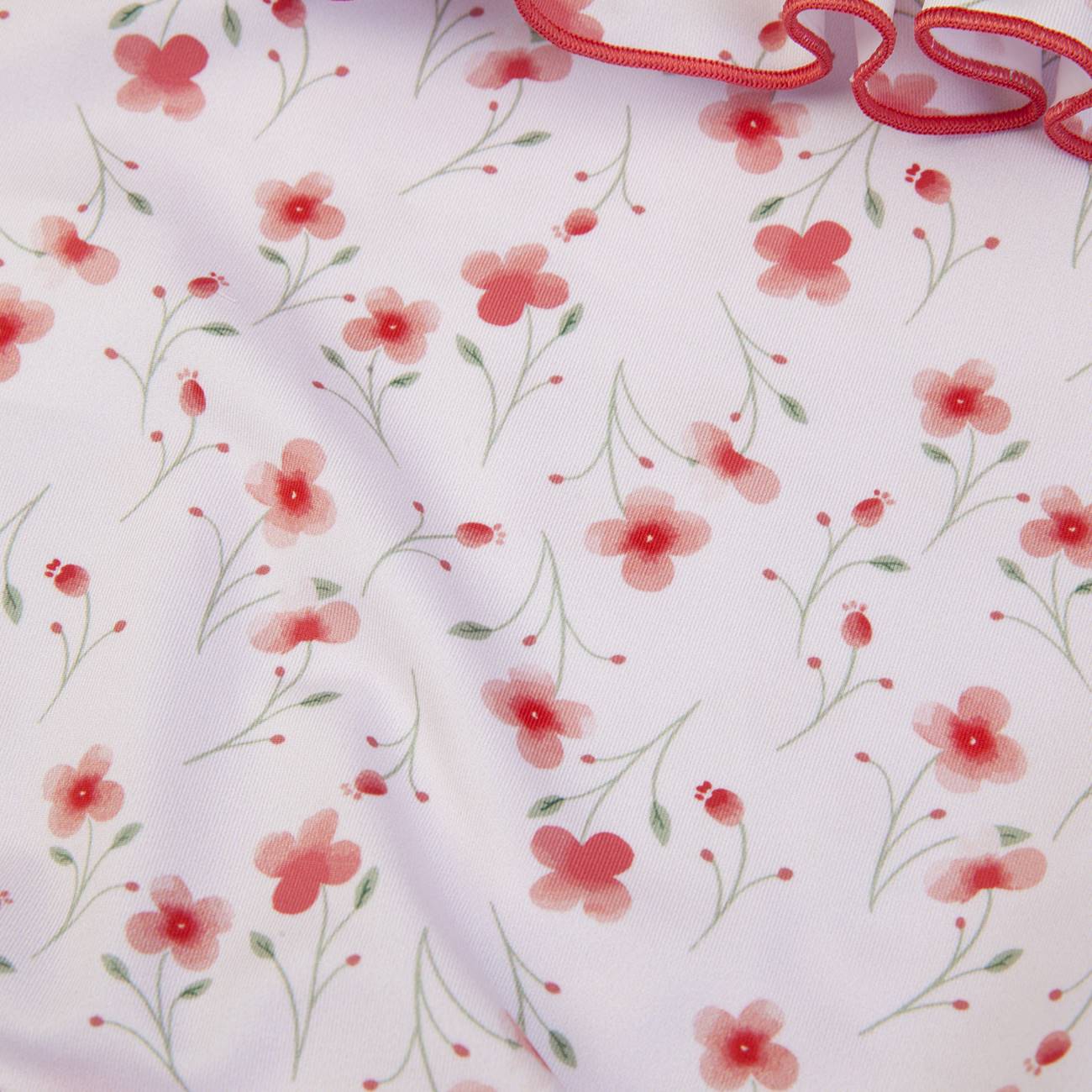 tecido branco com padrão floral vermelho e verde e fita ondulada vermelha