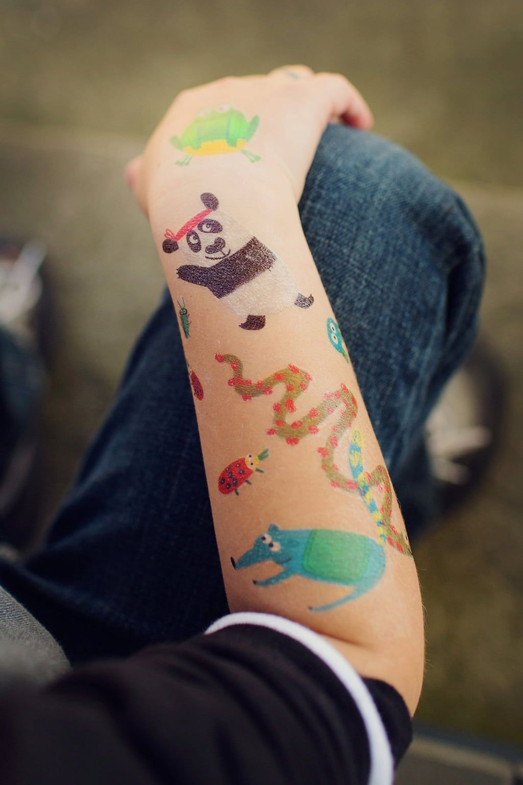 Braço com tatuagens temporárias coloridas de animais e insetos