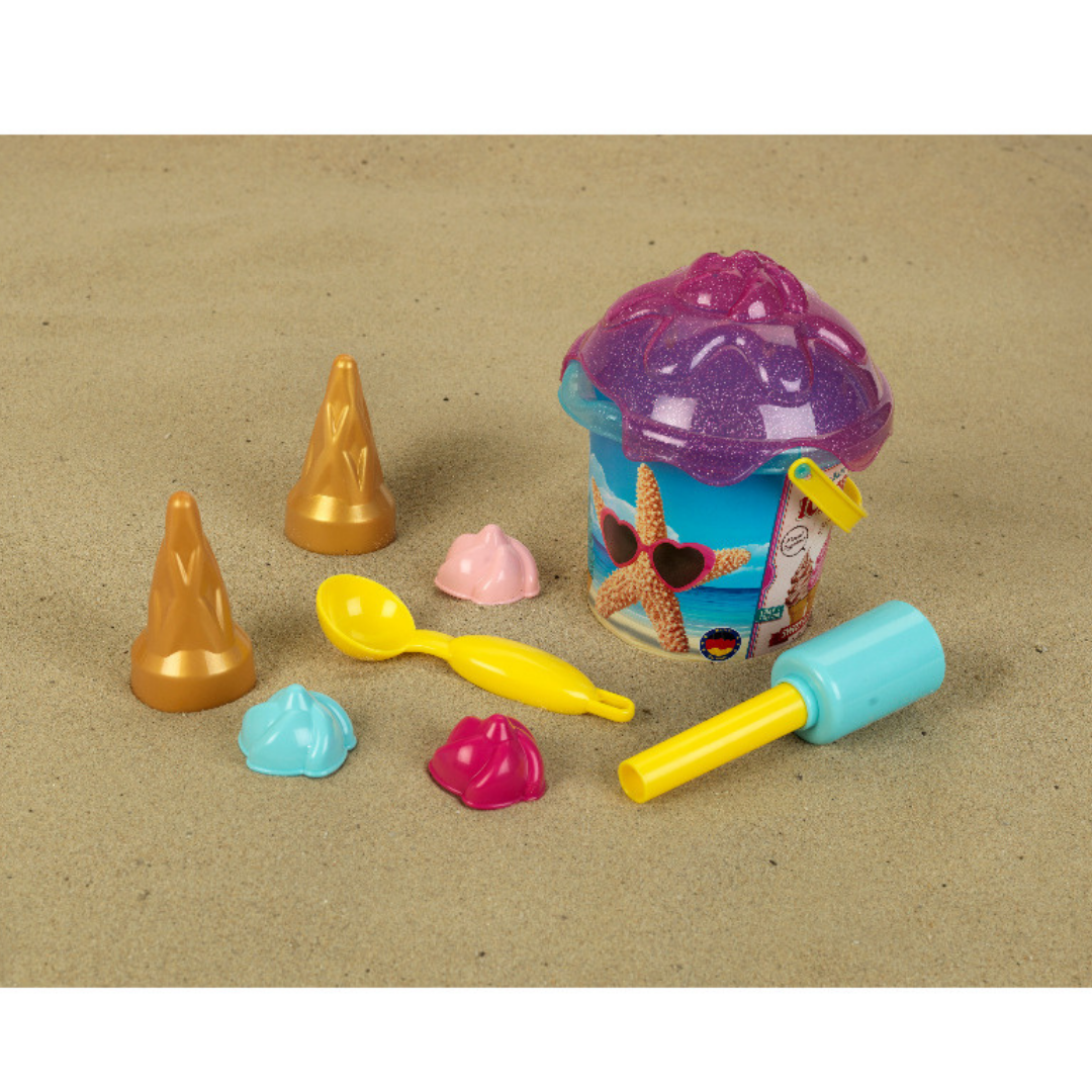 Brinquedos de praia para crianças num balde azul com tampa roxa e moldes coloridos na areia