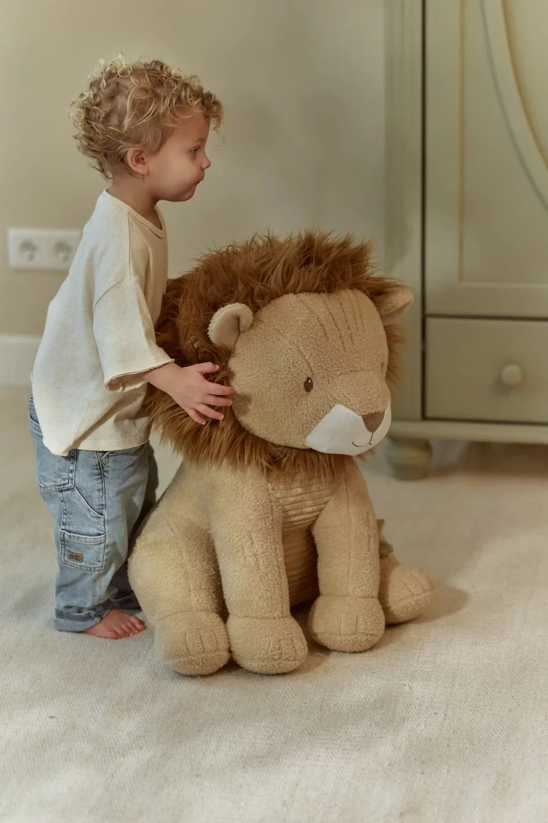 Criança pequena com peluche de leão grande