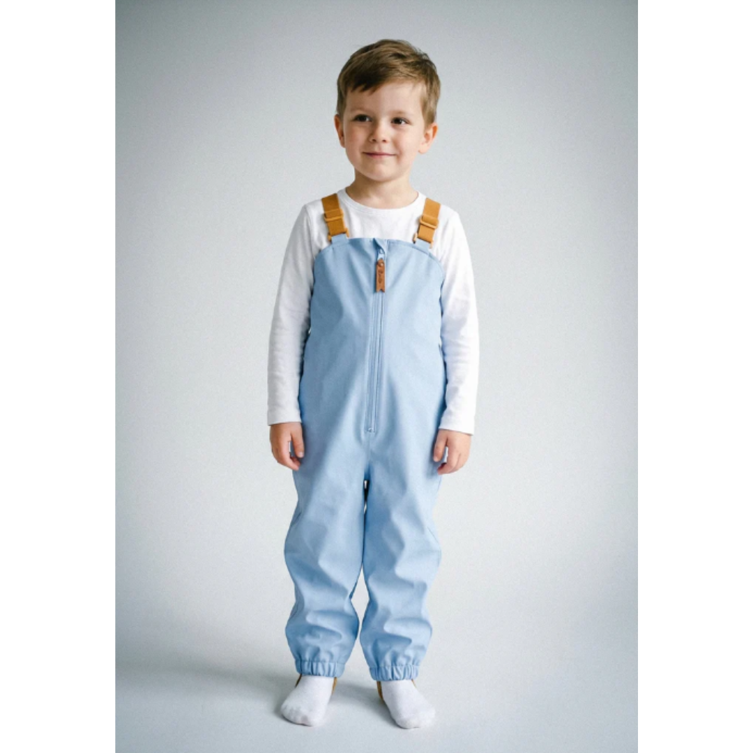 Criança com macacão azul claro e t-shirt branca de manga comprida