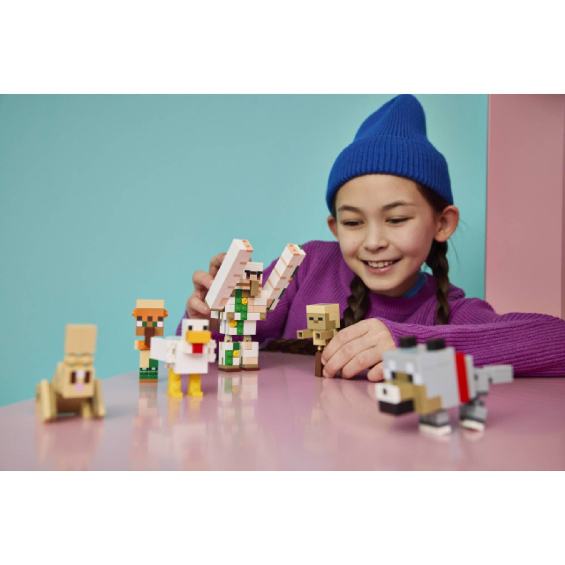 Menina a brincar com figuras de blocos de construção coloridos numa mesa cor de rosa.