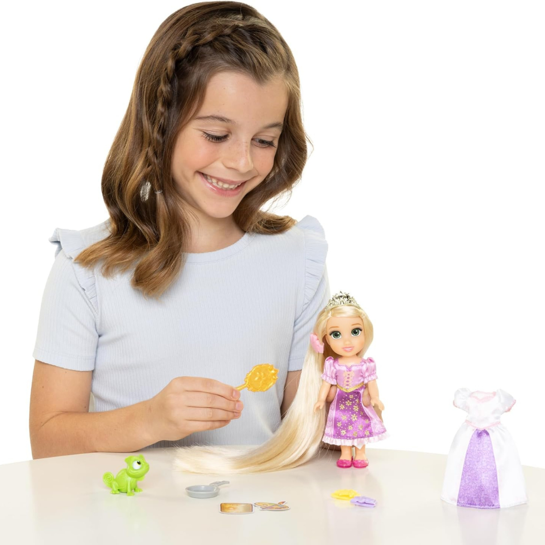 Menina a brincar com boneca Rapunzel e acessórios numa mesa branca