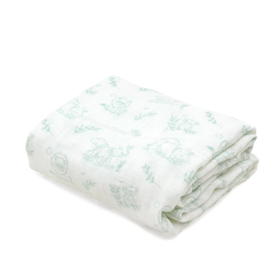 Manta branca com desenhos verdes de animais dobrada