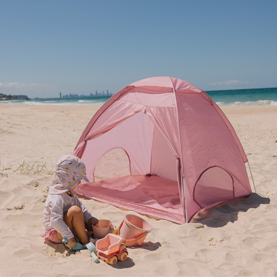Tenda de praia rosa com criança e brinquedos na areia