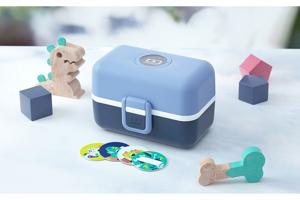 Estojo azul com brinquedos de madeira e cartas coloridas sobre superfície branca