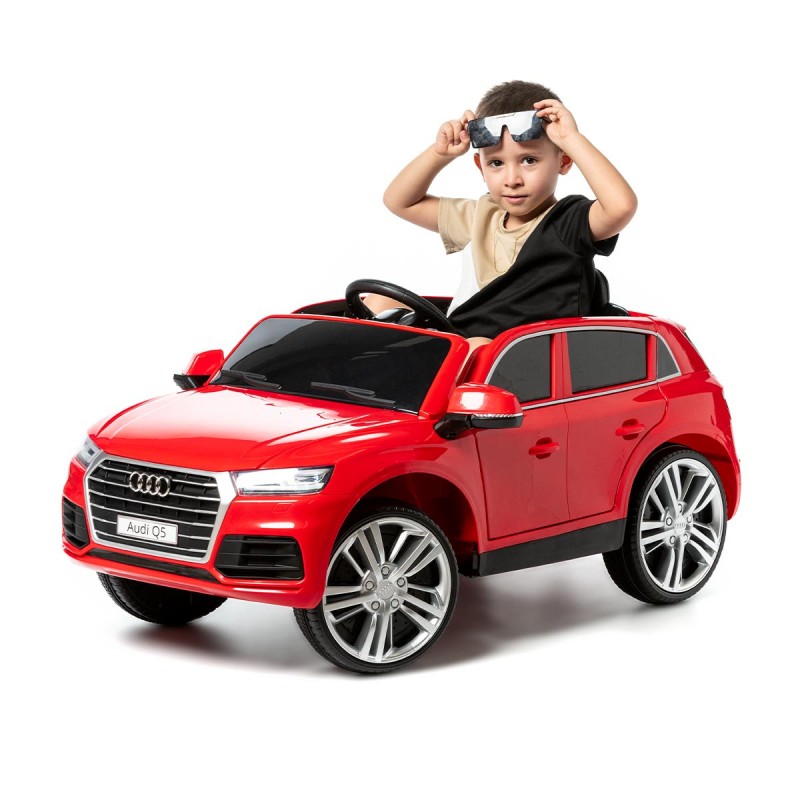 Criança com um carro de brinquedo Audi Q5 vermelho