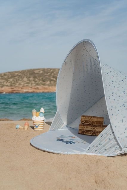 Tenda de praia cinzenta com padrão colorido na areia junto ao mar
