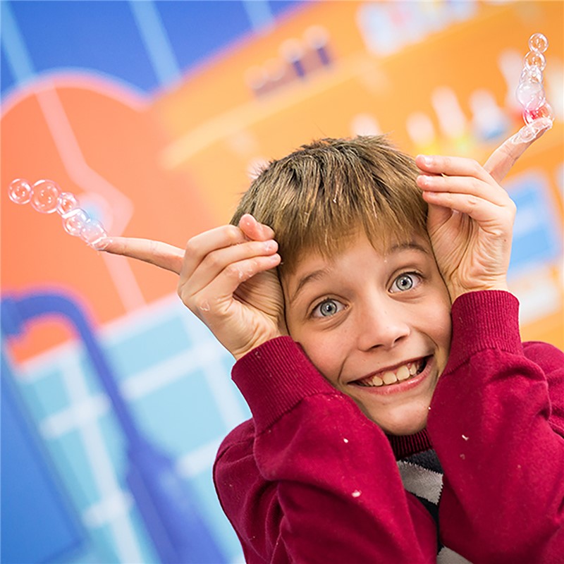 Criança com bolhas de sabão num fundo colorido