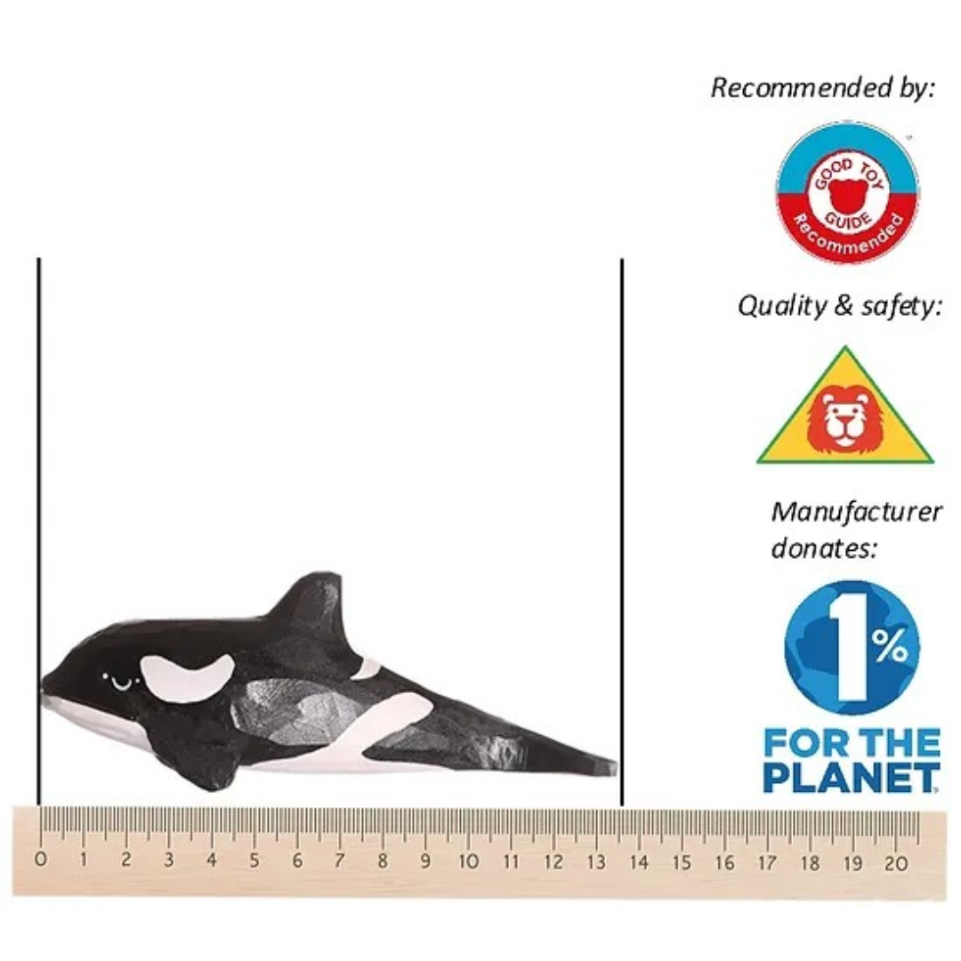 Figura de baleia orca preta e branca em madeira ao lado de régua em fundo branco com logos e textos.
