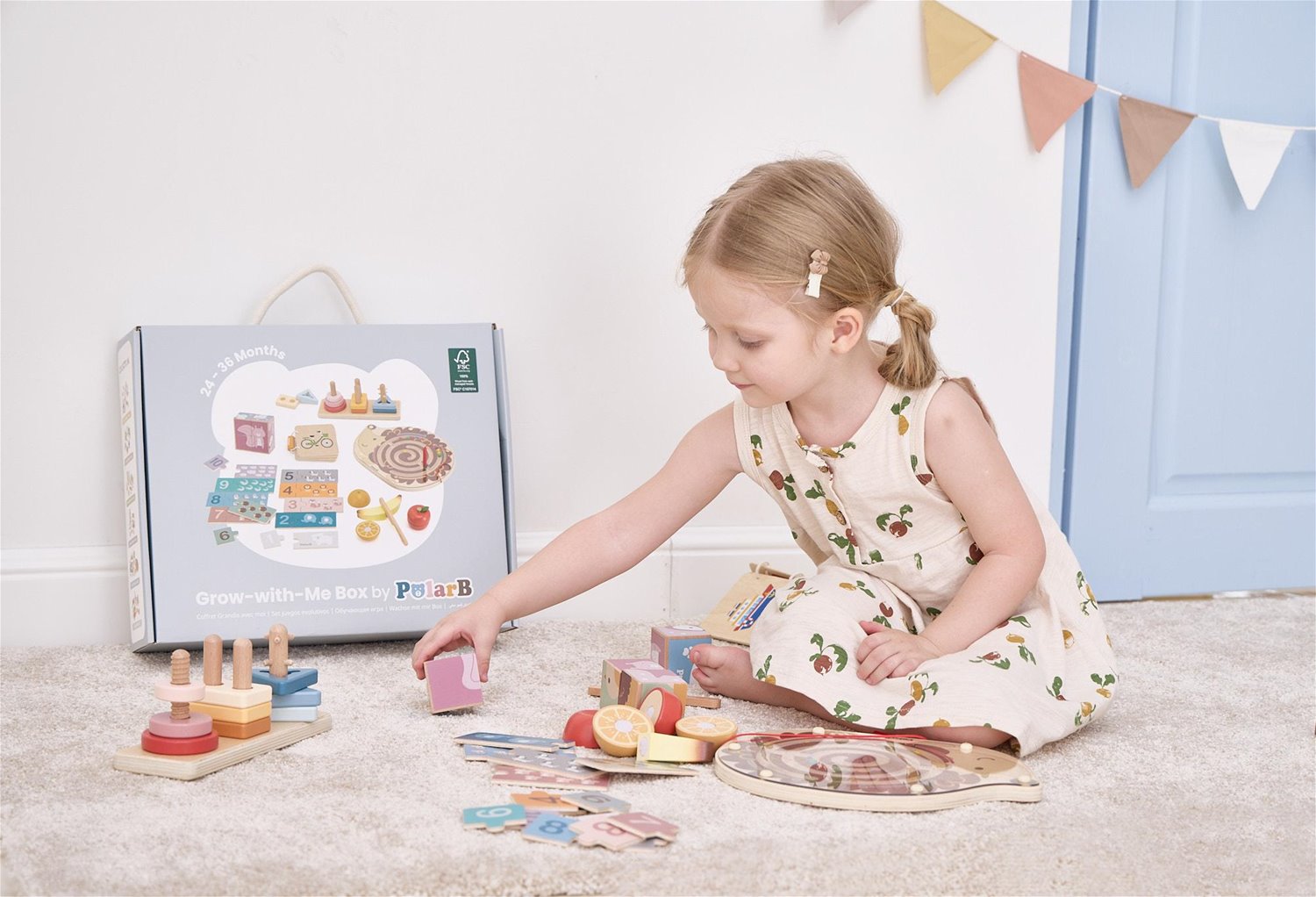 Criança a brincar com brinquedos educativos de madeira coloridos e caixa do produto