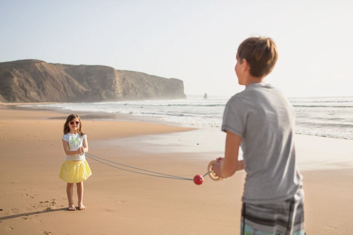 Duas crianças brincando com brinquedo de madeira na praia