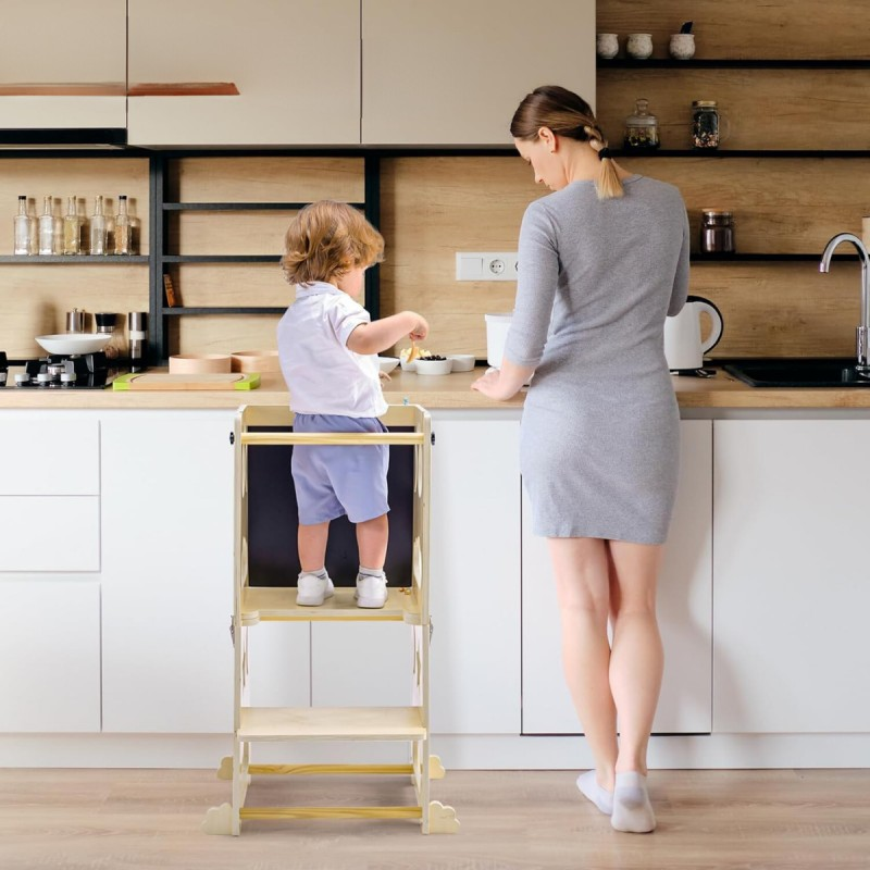 Criança numa escada de aprendizagem amarela na cozinha com mulher ao lado