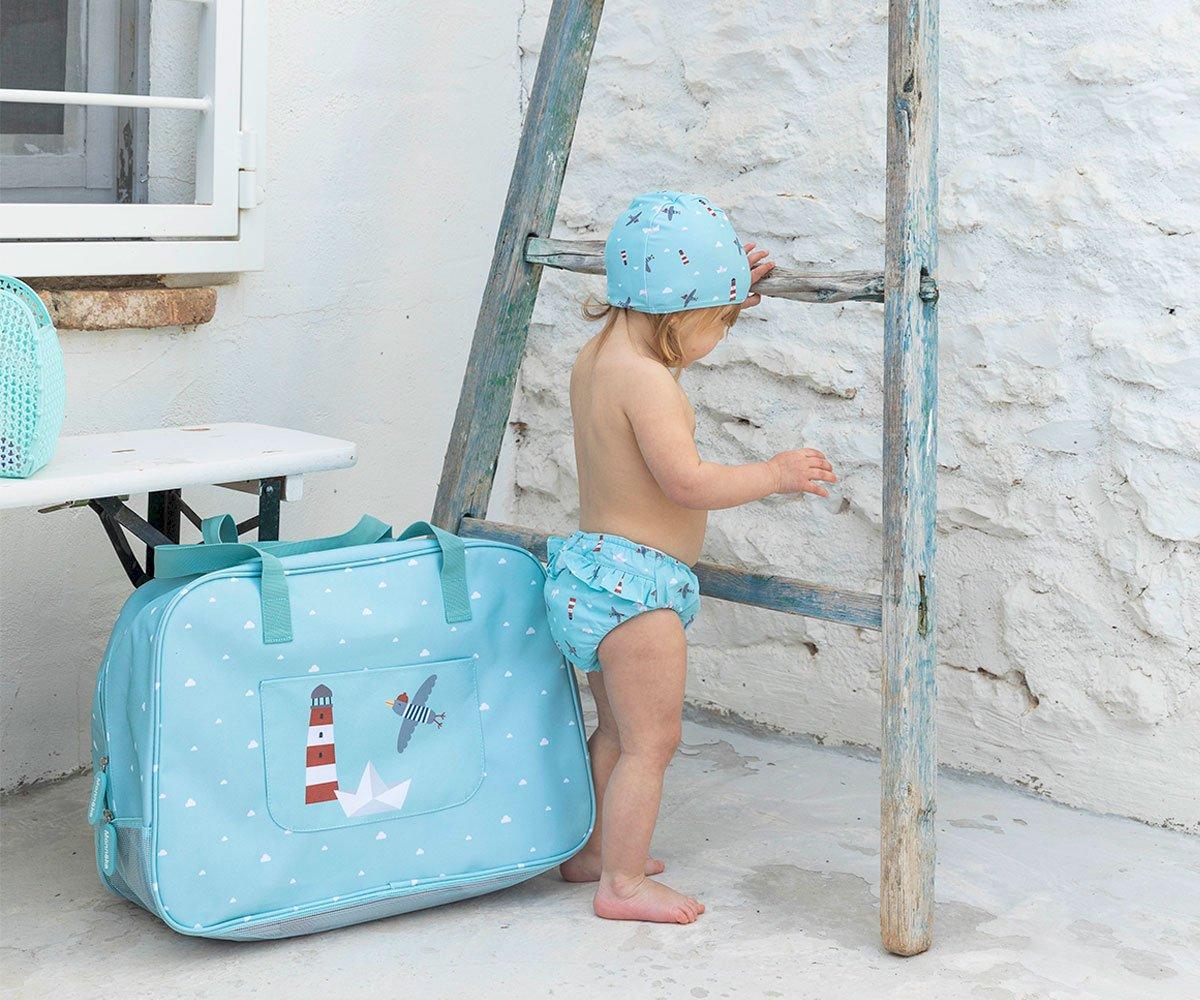 Bolsa azul clara com padrão náutico ao lado de criança junto a escada de madeira