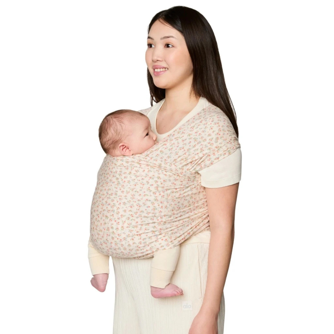 Sling floral creme usado por mulher segurando bebé