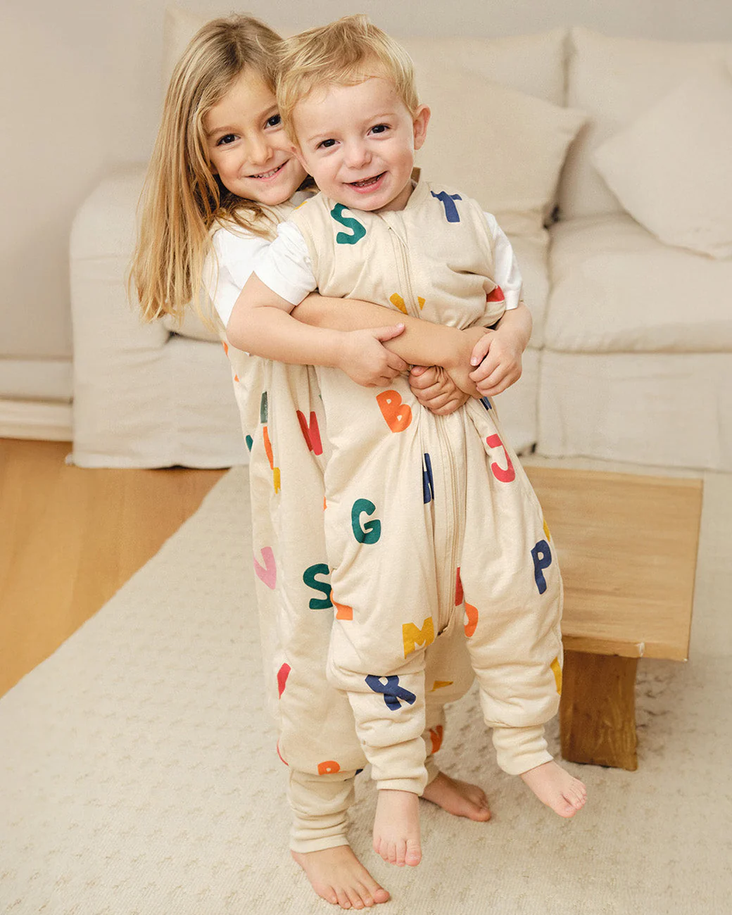 Crianças com pijamas bege estampados com letras coloridas em ambiente interior