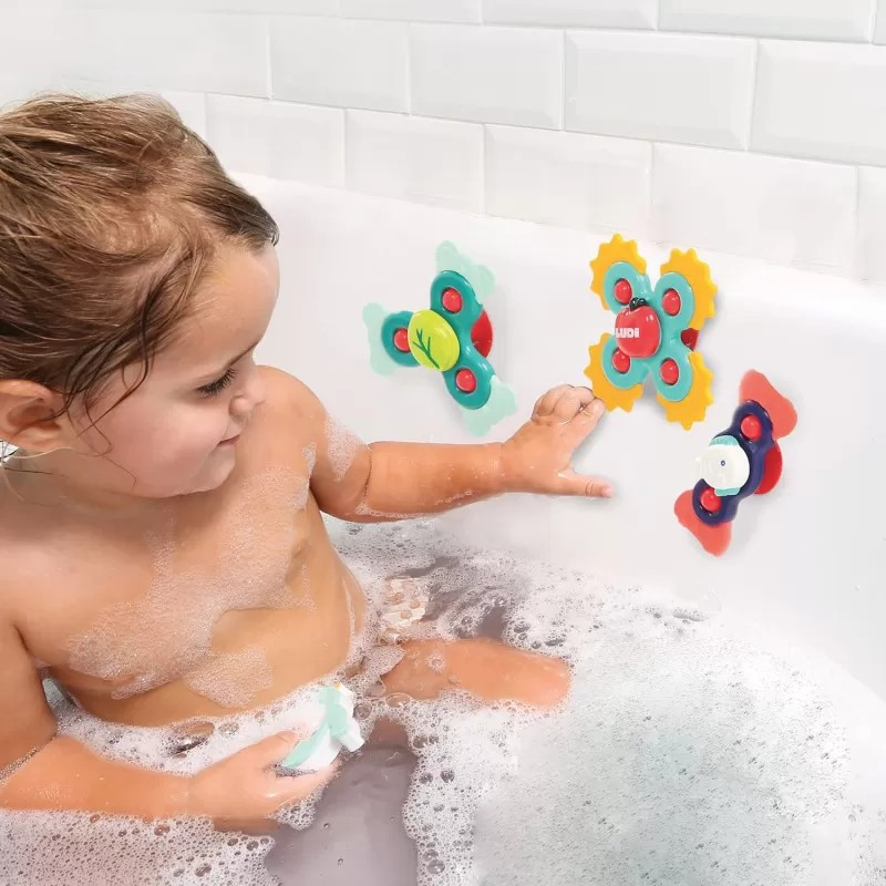 Criança na banheira a brincar com brinquedos de banho coloridos em parede branca