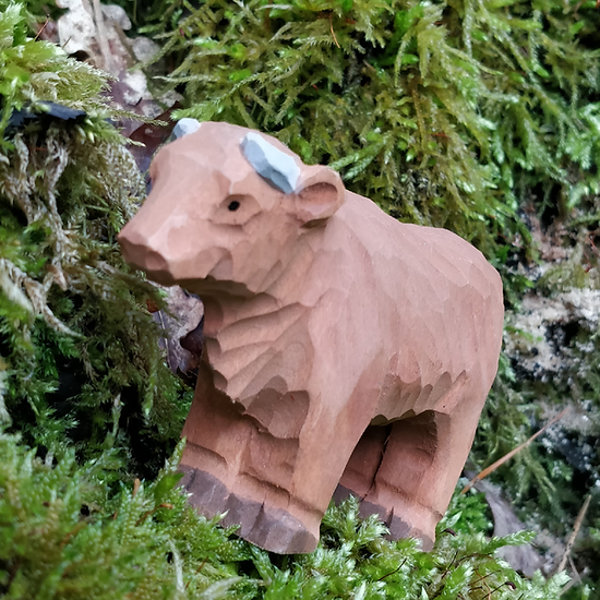 Miniatura de vaca de madeira castanha sobre musgo verde