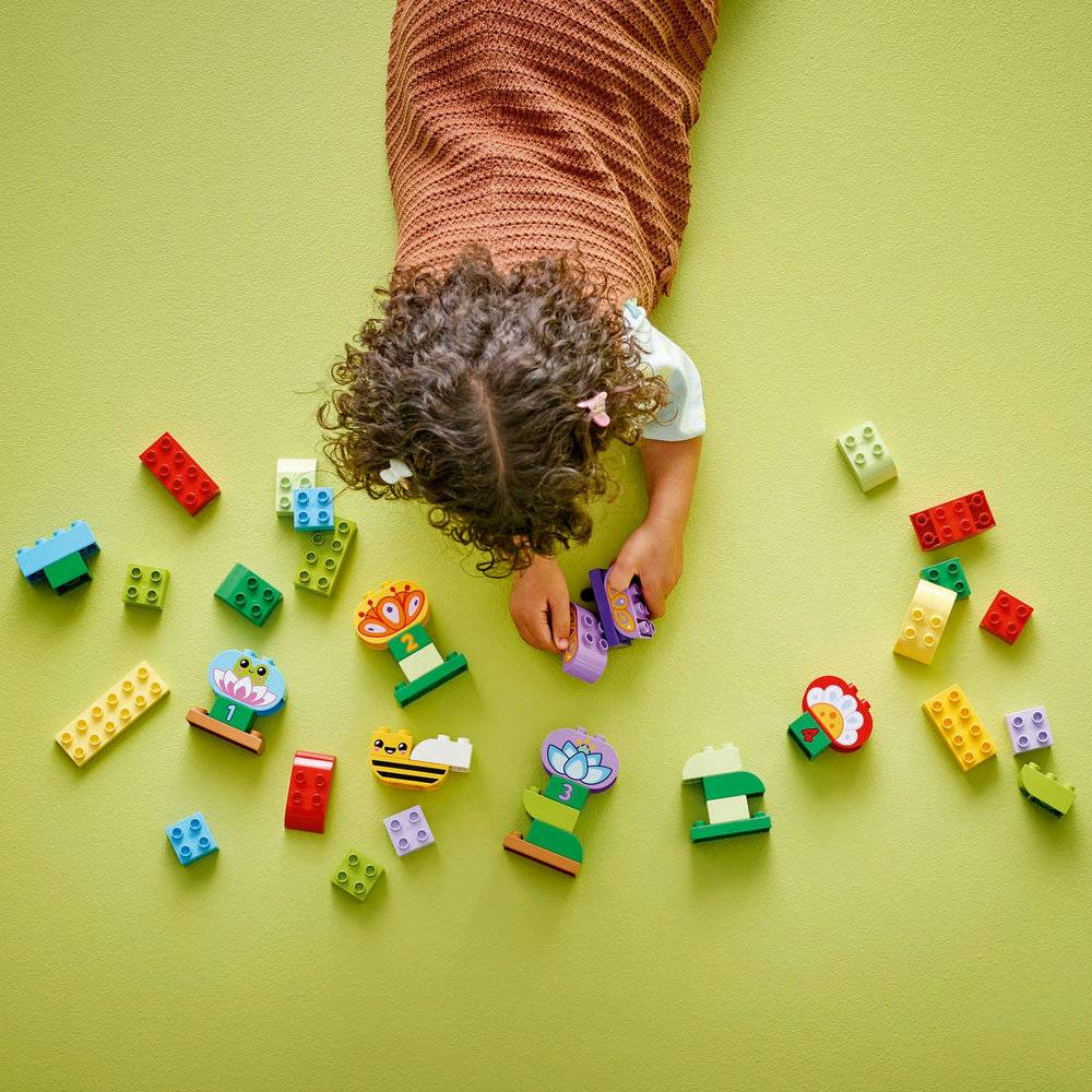 Criança a brincar com blocos de construção coloridos sobre fundo verde