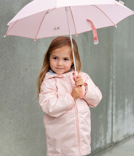 Menina com casaco e guarda-chuva rosa claro junto a parede de concreto cinzenta