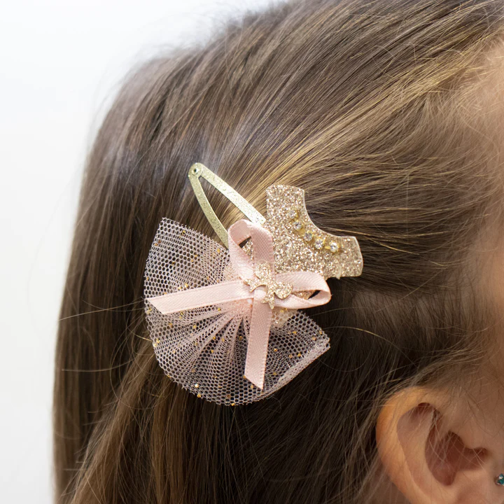 Presilha de cabelo dourada com malha rosa e laço aplicada em cabelo castanho claro