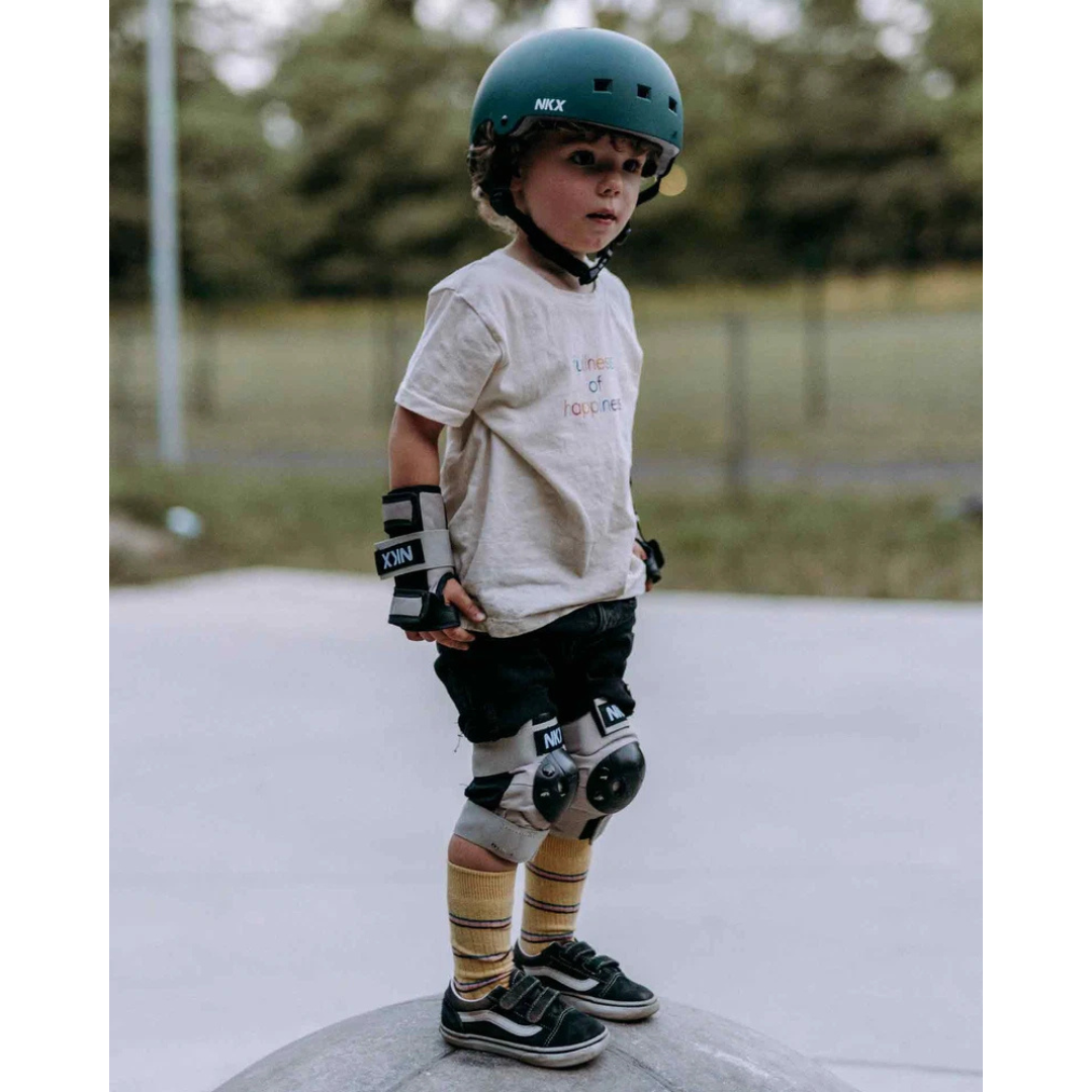 Criança com capacete e equipamentos de proteção para skate a olhar para frente
