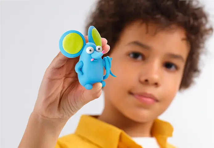 Figura de massa moldável azul com orelhas verdes e azuis segurada por criança.