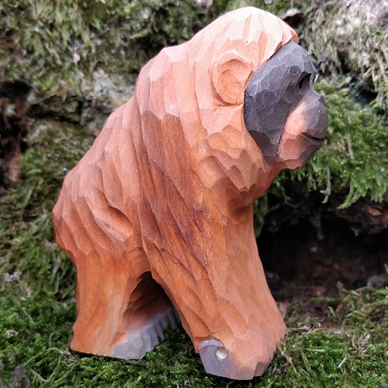 Escultura de madeira facetada de macaco marrom e cinza sobre musgo