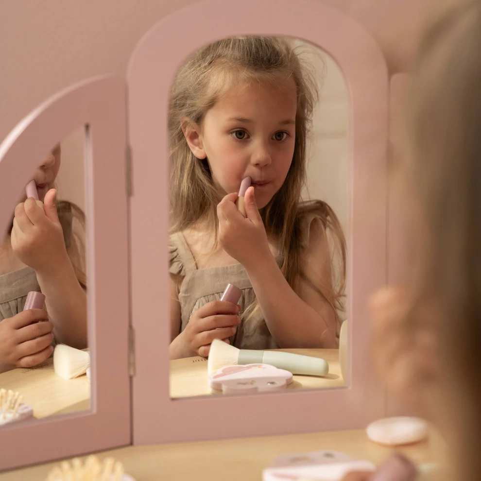Espelho de mesa cor-de-rosa com menina maquilhando-se com batom